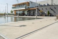 the woman is looking at the large building and pool area beside the building, with many plants