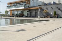 the woman is looking at the large building and pool area beside the building, with many plants