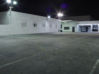 empty parking lot with the lighting on and building in the background with street lights on