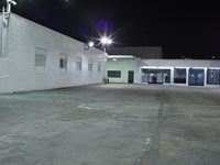 empty parking lot with the lighting on and building in the background with street lights on