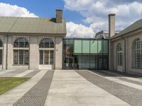 a sidewalk in front of some windows and a building with stone tiles and gravel paths in front of it