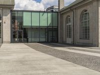 a sidewalk in front of some windows and a building with stone tiles and gravel paths in front of it