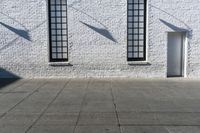 a building with three windows and a red fire hydrant outside it and shadows on the wall