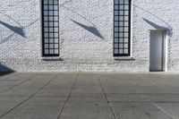 a building with three windows and a red fire hydrant outside it and shadows on the wall