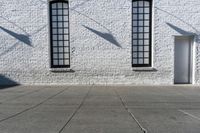 a building with three windows and a red fire hydrant outside it and shadows on the wall