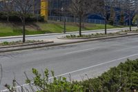 a bus stop on a city street next to a row of bushes and bushes at one end of the road