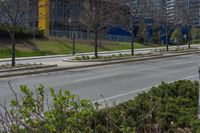 a bus stop on a city street next to a row of bushes and bushes at one end of the road