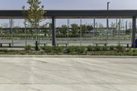 a bus stop with many windows in the background on a sunny day, it appears to be in a public transit area