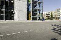 a young man rides down a busy road with a blue scooter in front of a large building