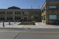 empty street corner next to old brick building and street lamp pole with metal barriers behind them