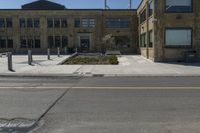 empty street corner next to old brick building and street lamp pole with metal barriers behind them