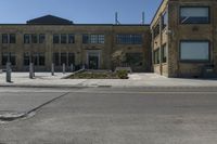 empty street corner next to old brick building and street lamp pole with metal barriers behind them