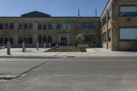 empty street corner next to old brick building and street lamp pole with metal barriers behind them