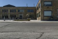 empty street corner next to old brick building and street lamp pole with metal barriers behind them