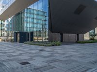 a large building with lots of glass front windows and some benches below it a blue wall