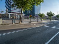 an empty street in front of a building and trees on the other side of the road