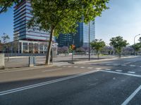 an empty street in front of a building and trees on the other side of the road