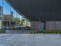 a modern and modern courtyard with an artistic wall that has many large windows reflecting the city's buildings