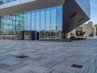 an outdoor area with a tiled floor, and a tall glass building near by with a red stop light