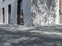 a man riding a skateboard past a building that has windows and a white fence