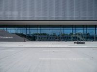 there are many people walking in front of the building, that appears to be covered with glass