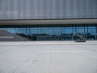 there are many people walking in front of the building, that appears to be covered with glass