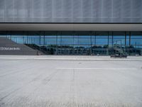 there are many people walking in front of the building, that appears to be covered with glass