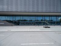 there are many people walking in front of the building, that appears to be covered with glass