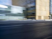 a black truck driving on a city street near buildings, bluring at the camera