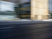 a black truck driving on a city street near buildings, bluring at the camera