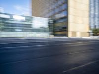 a black truck driving on a city street near buildings, bluring at the camera