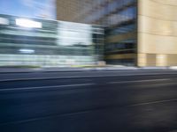 a black truck driving on a city street near buildings, bluring at the camera