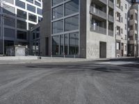 an empty street with tall building in the background and a graffiti on the ground below