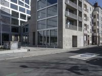 an empty street with tall building in the background and a graffiti on the ground below