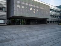 an empty area in front of a building with large windows and a stone floor underneath it