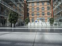 an empty walkway in front of a very tall building with glass walls and some trees