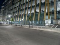 a picture of a large glass and steel building at night with some lights on the side of it