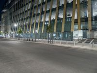 a picture of a large glass and steel building at night with some lights on the side of it