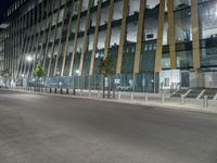 a picture of a large glass and steel building at night with some lights on the side of it