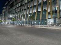 a picture of a large glass and steel building at night with some lights on the side of it