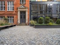 an empty parking lot with plants in the ground and on the side of the building, there is an enclosed area and windows