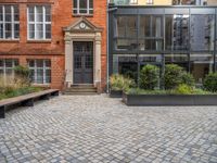 an empty parking lot with plants in the ground and on the side of the building, there is an enclosed area and windows