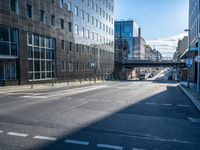 a empty street with traffic signs at the intersection of it and skyscrapers in the background