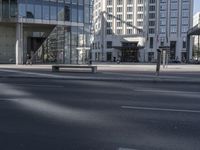 a street in front of an office building, in a city setting with a bench