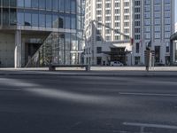 a street in front of an office building, in a city setting with a bench