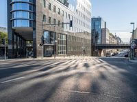 a view down a street from an office building in the distance, near an intersection with a pedestrian crossing