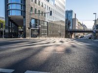 a view down a street from an office building in the distance, near an intersection with a pedestrian crossing