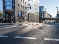 a view down a street from an office building in the distance, near an intersection with a pedestrian crossing