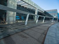 a train platform near the street of a large building with glass windows and large windows