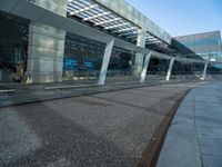 a train platform near the street of a large building with glass windows and large windows